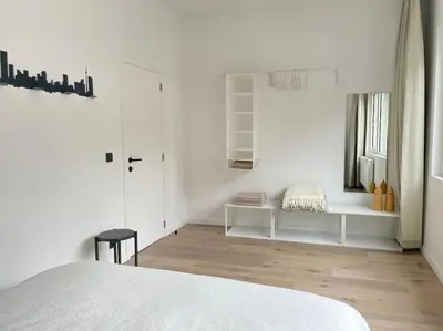 a white room with a white bed and a wooden floor at #2800ourhome 201 in Mechelen