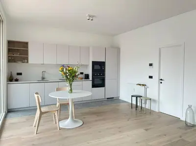 a white kitchen with a table and a vase of flowers at #2800ourhome 201 in Mechelen
