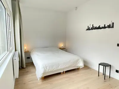 a white bedroom with a bed and a window at #2800ourhome 201 in Mechelen