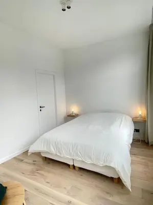 a white bedroom with a white bed and two lamps at #2800ourhome 202 in Mechelen