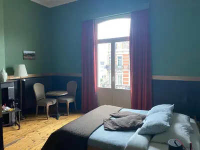 a bedroom with a bed and a window and a table at Vakantielogies Faja lobi in Ghent