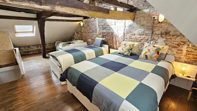 a bedroom with two beds and a brick wall at CEP ECUYER in Brussels