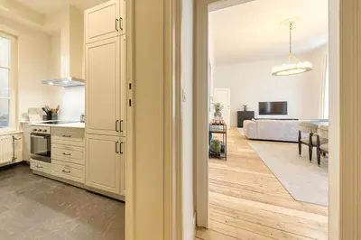 a kitchen with white cabinets and a living room at Appartement dans l'hypercentre in Brussels