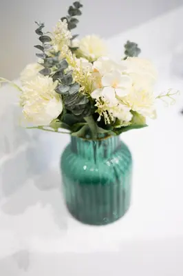 a green vase filled with white flowers on a table at Appartement dans l'hypercentre in Brussels