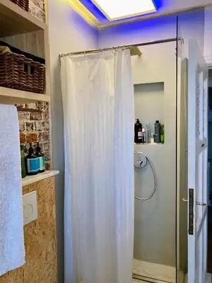 a shower with a white shower curtain in a bathroom at Calm, green & birdsong in Brussels