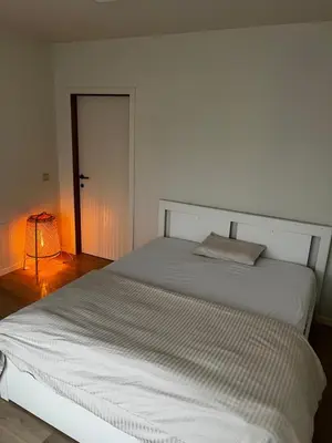 a white bedroom with a large white bed with a lamp at Budget Flex in Geel