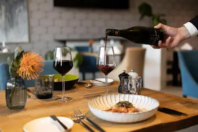 a person pouring a glass of wine over a plate of food at voco Brussels City North by IHG in Vilvoorde