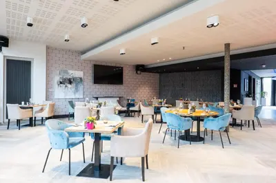 a dining room with tables and chairs and a tv at voco Brussels City North by IHG in Vilvoorde