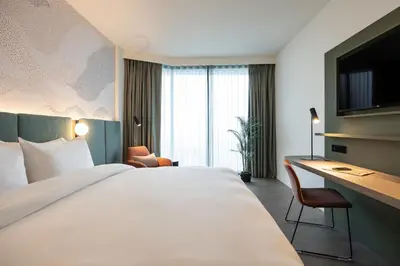 a hotel room with a large bed and a desk at voco Brussels City North by IHG in Vilvoorde