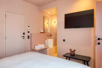 a bedroom with a bed with a flat screen tv on the wall at Maison Arya in Brussels