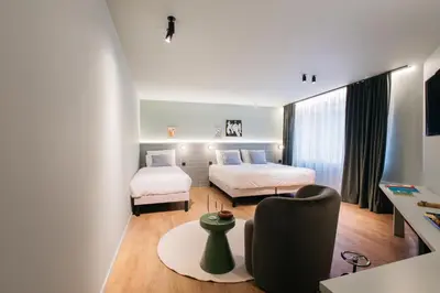 a hotel room with two beds and a chair at Maison Arya in Brussels