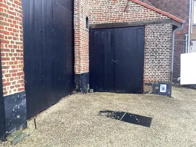 a black garage door in a brick building at Gastroatelier in Gooik