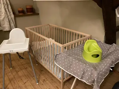a crib with a green chair in a room at Gastroatelier in Gooik