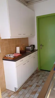 a kitchen with white cabinets and a green door at Feel at home in Leuven in Leuven