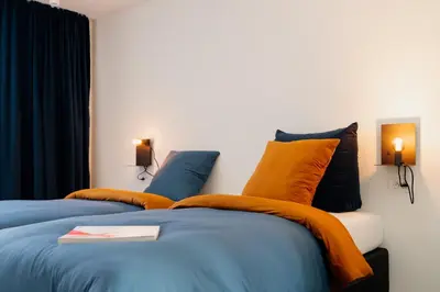 a bedroom with two beds with orange and blue pillows at Befour Vakantiewoning in Aalst
