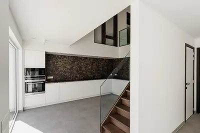 a staircase in a white kitchen with a glass railing at Befour Vakantiewoning in Aalst