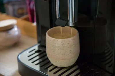 a cup of coffee is being poured into a coffee machine at B&B Kraneveld in Haacht