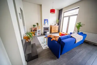 a living room with a blue couch and a window at Casa Mina - Dok Noord Ghent in Ghent