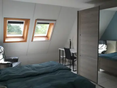a bedroom with a bed and a desk and windows at logies 'Raapbreuk' in Herentals