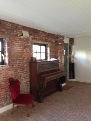 a room with a piano and a brick wall at B&B Droomzoet in Herentals