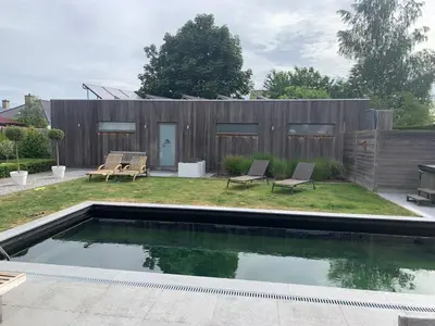 a backyard with a swimming pool and a wooden fence at Q Guesthouse in Herzele