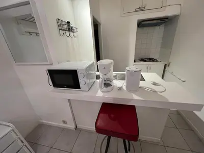 a white counter with a microwave and a red chair at Appartements Brussels in Brussels