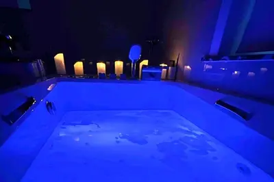 a bath tub with blue lighting in a room with candles at Sublime appartement Calme Cosy & Jacuzzi in Brussels