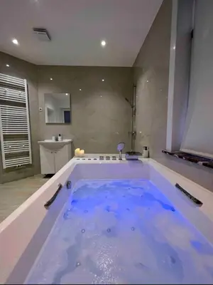 a large bath tub with blue water in a bathroom at Sublime appartement Calme Cosy & Jacuzzi in Brussels