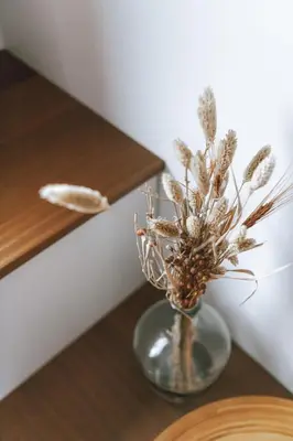 a glass vase with dried flowers in it on a table at Imagine Tiny House 325 op Camping GT te Balen in Balen