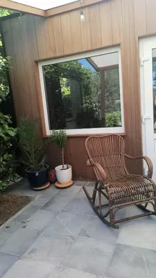 a rocking chair on a patio with a window at Imagine Tiny House 325 op Camping GT te Balen in Balen