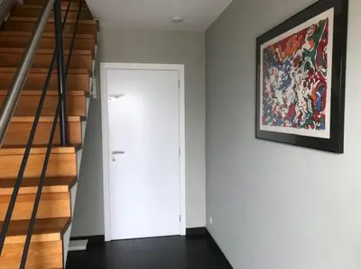 a hallway with a white door and a painting on the wall at Fokus Time out in Dessel