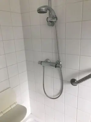 a shower in a white tiled bathroom with a toilet at Fokus Time out in Dessel