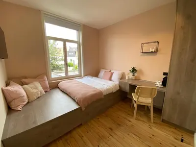 a bedroom with a bed with a window and a desk at Maison d’Arnaud in Ghent
