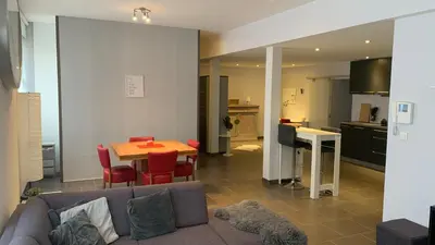 a living room with a couch and a table and a kitchen at Ruime studio in Deurne in Antwerp