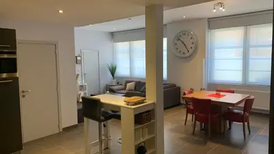 a kitchen and living room with a table and a clock at Ruime studio in Deurne in Antwerp