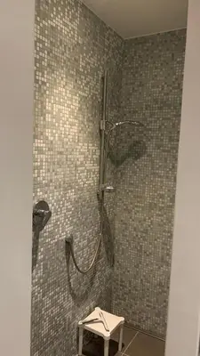 a shower in a bathroom with a tile wall at Ruime studio in Deurne in Antwerp