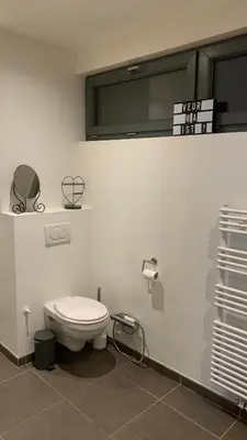 a bathroom with a toilet and a sign on the wall at Ruime studio in Deurne in Antwerp