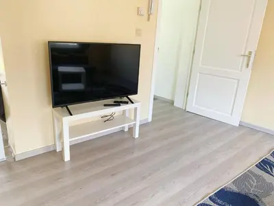 a flat screen tv sitting on a white stand in a room at Sweet home with big terrace in Brussels