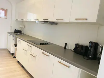 a kitchen with white cabinets and a black counter top at Sweet home with big terrace in Brussels