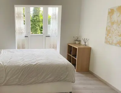 a white bedroom with a bed and a window at Sweet home with big terrace in Brussels