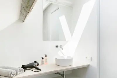 a white bathroom with a sink and a mirror at High-end flats at South area in Antwerp
