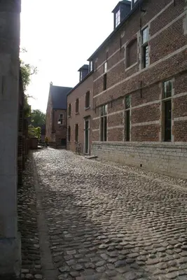 an empty cobblestone street next to a brick building at Guest House Feliz in Leuven