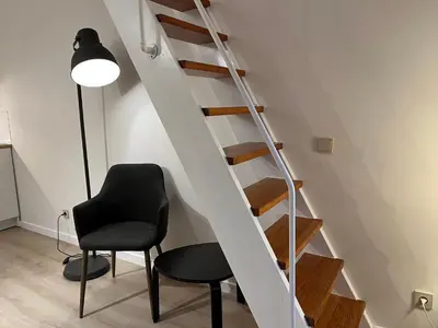 a black chair and a staircase in a room at Brussels center flat in Brussels