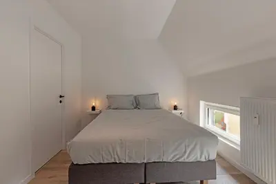 a white bedroom with a bed and a window at Märch - Mechelen Goat 21 in Mechelen