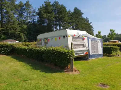 an rv parked in a field next to a hedge at Vakantiepark Breebos: Empty Lots for tents and mobile homes in Rijkevorsel
