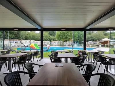 an empty restaurant with tables and chairs and a pool at Vakantiepark Breebos: Empty Lots for tents and mobile homes in Rijkevorsel