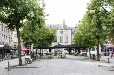 a city street with people sitting at tables and umbrellas at High-end 3BDR apartment @ city center in Antwerp
