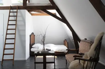 a attic room with a bed and a ladder at Edville Home in Ghent