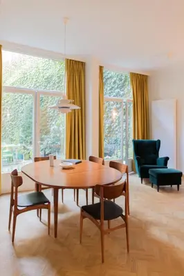 a living room with a wooden table and chairs at Pauline Loveling apartment with quiet garden and 2 bathrooms in Antwerp