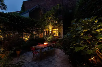 a table in a garden at night with a candle on it at Carriage House in quiet ecological garden in Antwerp